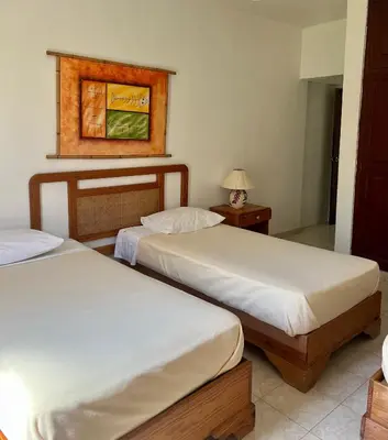 a bedroom with two beds and a table with a lamp at Hotel Angel Gabriel in Boca Chica