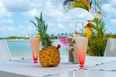 a table with a pineapple and drinks on the beach at 1st Line view in San Pedro de Macorís