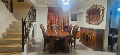 a dining room with a wooden table and a staircase at Paraíso en Repúblico Dominicana in Santiago de los Caballeros