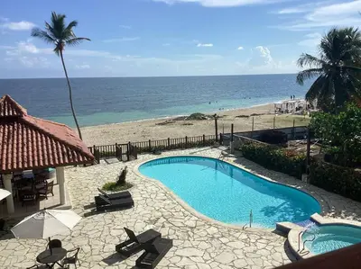 a swimming pool next to a beach with the ocean at Apartment with ocean front view in Juan Dolio