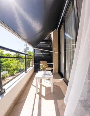 a balcony with a chair and large windows at Las Golondrinas Cabarete in Cabarete