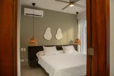 a bedroom with a bed and two pendant lights at Las Golondrinas Cabarete in Cabarete