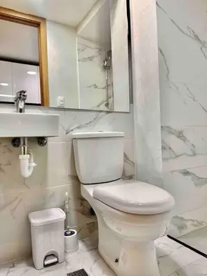 a white bathroom with a toilet and a sink at Comfy 2BR City Center Condo in Los Prados