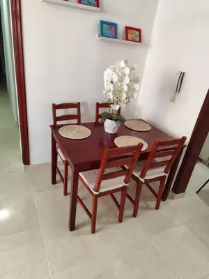a wooden table with four chairs and a vase with flowers at Your Tropical HouseRD in La Francia