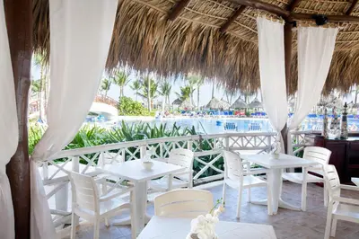 a restaurant with white tables and chairs and a pool at Bahia Principe Grand Punta Cana - All Inclusive in Punta Cana