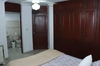 a bedroom with a bed and a wooden closet at Three-Bedroom Apartment 3 in Santo Domingo