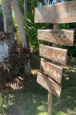 a sign with several signs in front of a tree at Beach, nature and relaxation in Las Terrenas