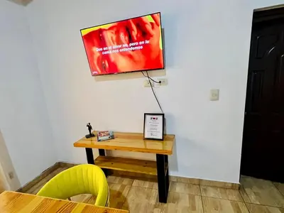 a tv hanging on a wall next to a table at Apartamento Brisas de la Montaña in Jarabacoa