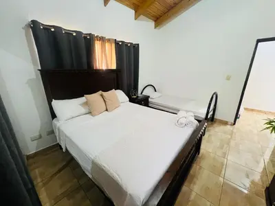 a bedroom with a large white bed with black curtains at Apartamento Brisas de la Montaña in Jarabacoa