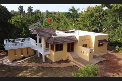 a small yellow house with a porch and a balcony at Villa LiMar in Río San Juan