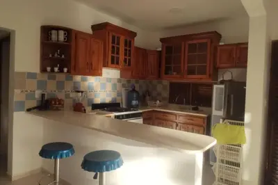 a kitchen with wooden cabinets and blue stools at Villa LiMar in Río San Juan