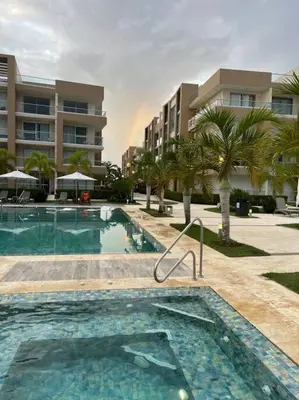 a swimming pool in front of a building with palm trees at Apartment in Playa Nueva Romana in San Pedro de Macorís