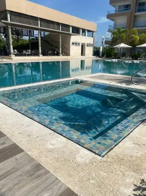 a swimming pool with blue tiles in front of a building at Apartment in Playa Nueva Romana in San Pedro de Macorís