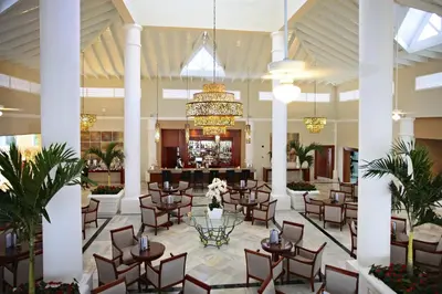 a lobby with tables and chairs and a bar at Bahia Principe Luxury Bouganville - Adults Only All Inclusive in La Romana