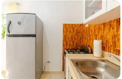 a small kitchen with a refrigerator and a sink at Escape to Puerto Plata, Cozy 2BR Loft in Las Mercedes, 5 Min from Beaches in Isabel de Torres