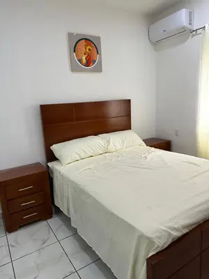 a bedroom with a bed with a wooden headboard at Apartamentos victoria in Las Terrenas