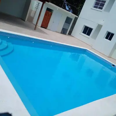 a blue swimming pool in front of a house at Hospedaje Lujoso en Boca Chica in Santo Domingo