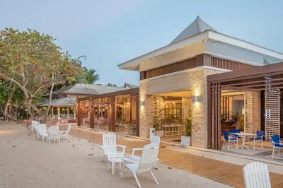 a building with white chairs and tables on a beach at Bahia Principe Grand El Portillo - All Inclusive in Las Terrenas