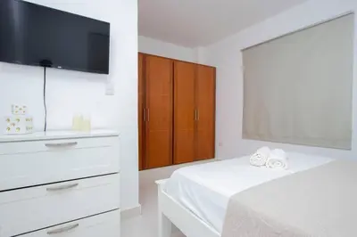 a bedroom with a bed with a dresser and a tv at APT 3 HAB Avenida España Piso 1 in La Viva
