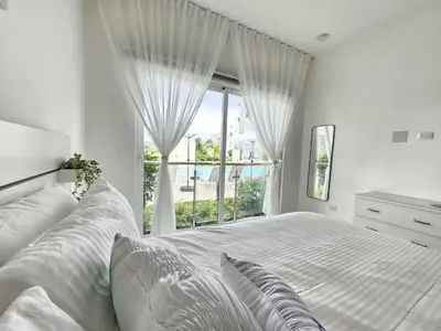 a white bedroom with a bed and a window at Melody 2BDR Condo with Pool View in Coral Bay #2 in Punta Cana