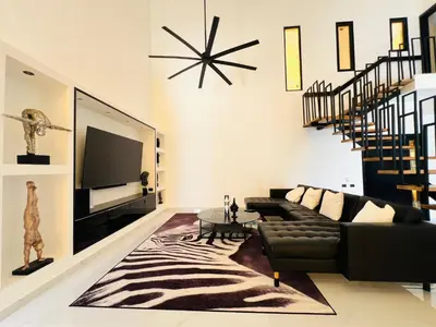 a living room with a black couch and a television at Casa B&W, Villa luxueuse Exceptionnelle, 8 personnes, à 1 min de la plage in Las Galeras