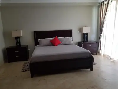 a bedroom with a bed with a red pillow at Hispaniola Luxury Ocean Front Condo in Sosúa