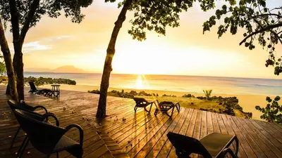 a wooden deck with chairs and a view of the ocean at Hispaniola Luxury Ocean Front Condo in Sosúa