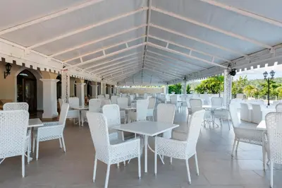 a row of tables and white chairs on a patio at Eurostars Grand Cayacoa in Santa Bárbara de Samaná