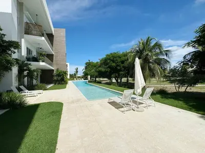 a patio with two chairs and an umbrella and a pool at Peaceful haven overlooking the golf course in Punta Cana