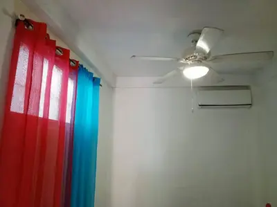 a ceiling fan in a room with a red and blue curtain at Acogedor apartamento entero in Mandinga