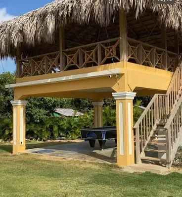 a large yellow house with a deck and a pool at Villa las Rosas JP in Bayaguana