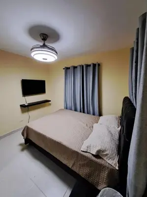 a bedroom with a bed and a flat screen tv at Maravilloso Apartamento Pequeño in Santo Domingo