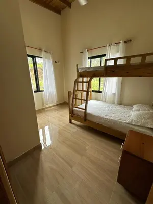 a bedroom with a bunk bed and two windows at Villa RG in Jarabacoa