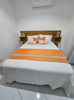 a bed with orange and white sheets and pillows at vista a toda la ciudad y montaña in San Felipe de Puerto Plata