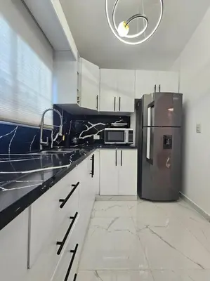 a kitchen with white cabinets and a refrigerator at vista a toda la ciudad y montaña in San Felipe de Puerto Plata