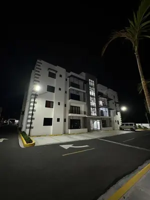 a large white building at night with a palm tree at RESIDENCIAL LEGADo in Azua de Compostela