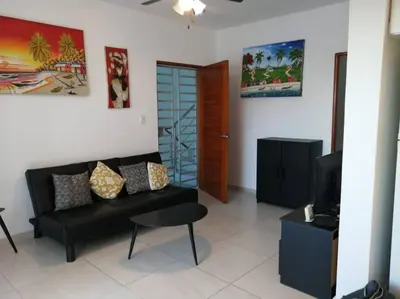 a living room with a black couch and a tv at Rincón de Tranquilidad in Bayahibe