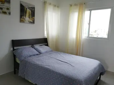a bedroom with a bed with a blue comforter and a window at Rincón de Tranquilidad in Bayahibe