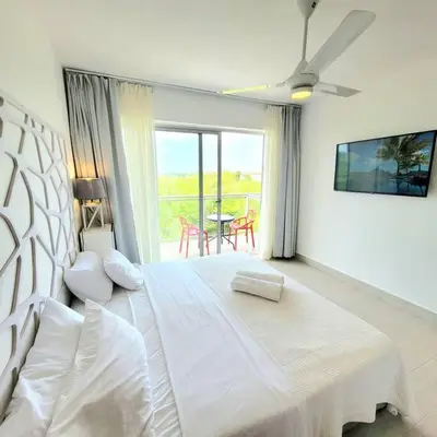 a white bedroom with a large bed with a ceiling fan at Gorgeous 2 bedroom apartment in Vibe Residence in Bayahibe