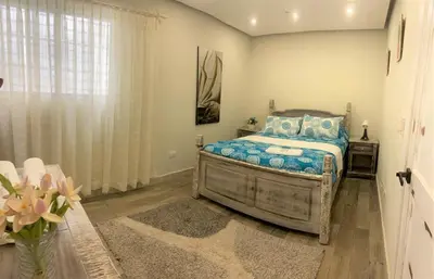 a bedroom with a bed with blue pillows and a window at Villa Ruben Juan Dolio in Juan Dolio