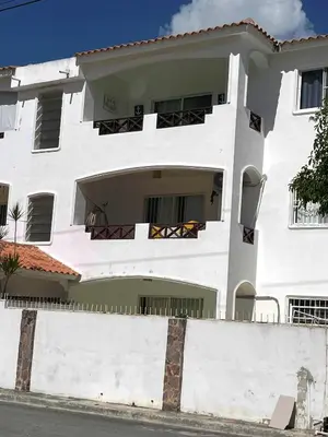 a white building with a fence in front of it at Apto CGM Esmeralda in Bayahibe