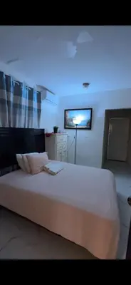 a bedroom with a large white bed with a blue light at Fantástico con luz aire tv y cocina in La Romana