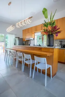 a kitchen with a long counter with chairs and a vase of flowers at Chameleon Village in El Limón
