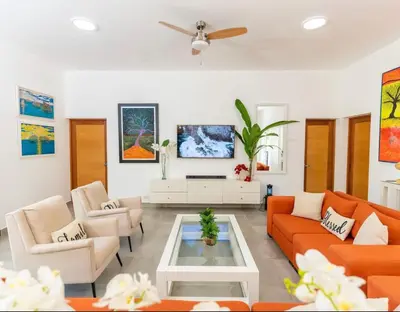 a living room with orange couches and a coffee table at Chameleon Village in El Limón