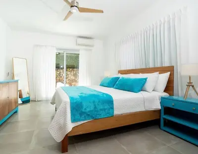 a bedroom with a large bed with blue pillows at Chameleon Village in El Limón