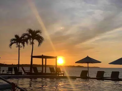 a pool with chairs and umbrellas and the sunset at Velero Beach Cabarete 2 bedroom Penthouse in Cabarete