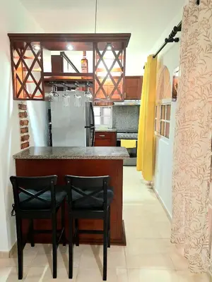 a kitchen with a bar with two black chairs at Apartamento Oasis PUNTA CANA in Punta Cana