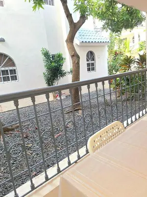 a bench sitting on a balcony next to a tree at Apartamento Oasis PUNTA CANA in Punta Cana