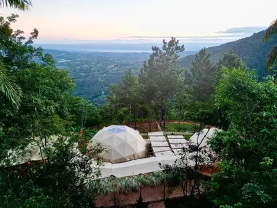 a white tent sitting on top of a hill at Nomad Dome at Salto Jimenoa Waterfall in Jarabacoa