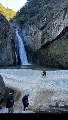 three people and a dog on a beach near a waterfall at Nomad Dome at Salto Jimenoa Waterfall in Jarabacoa
